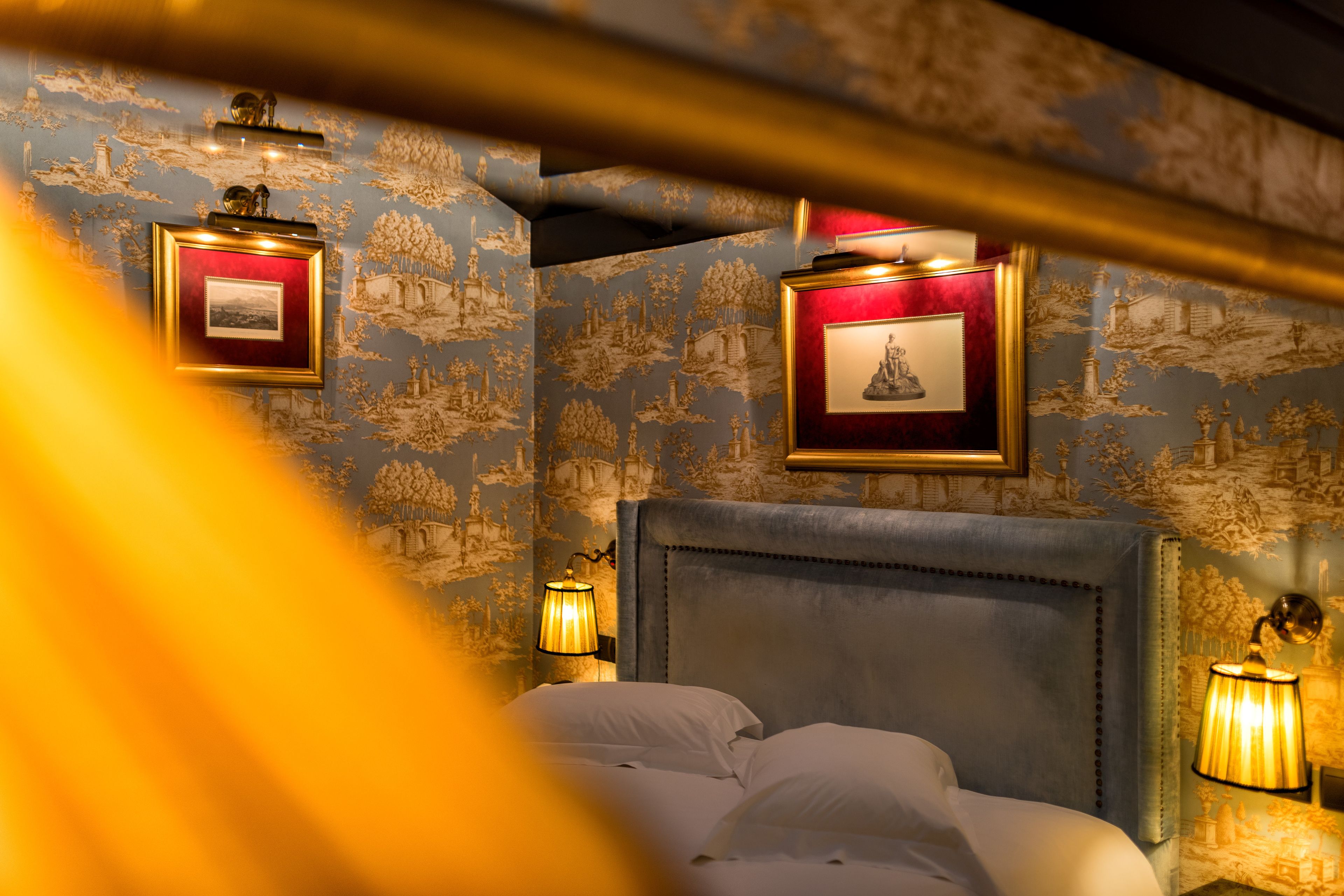 Habitación de hotel con una cama grande, dos lámparas de pared y dos cuadros en la pared.