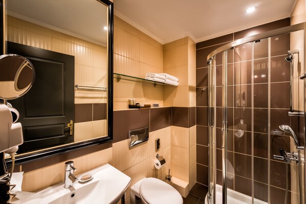 Un baño moderno con cabina de ducha de vidrio, un lavabo blanco y un espejo grande.