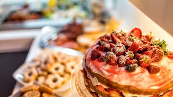 Un bufé de postres con una variedad de pasteles y dulces, incluyendo un pastel cubierto de fresas.