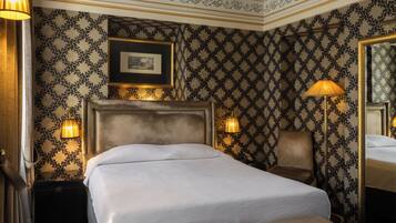 Een hotelkamer met een groot bed, twee bedlampjes, een ingelijste foto aan de muur en een spiegel.