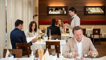 Un restaurante con paredes de paneles de madera, mesas blancas y centros de mesa con velas.