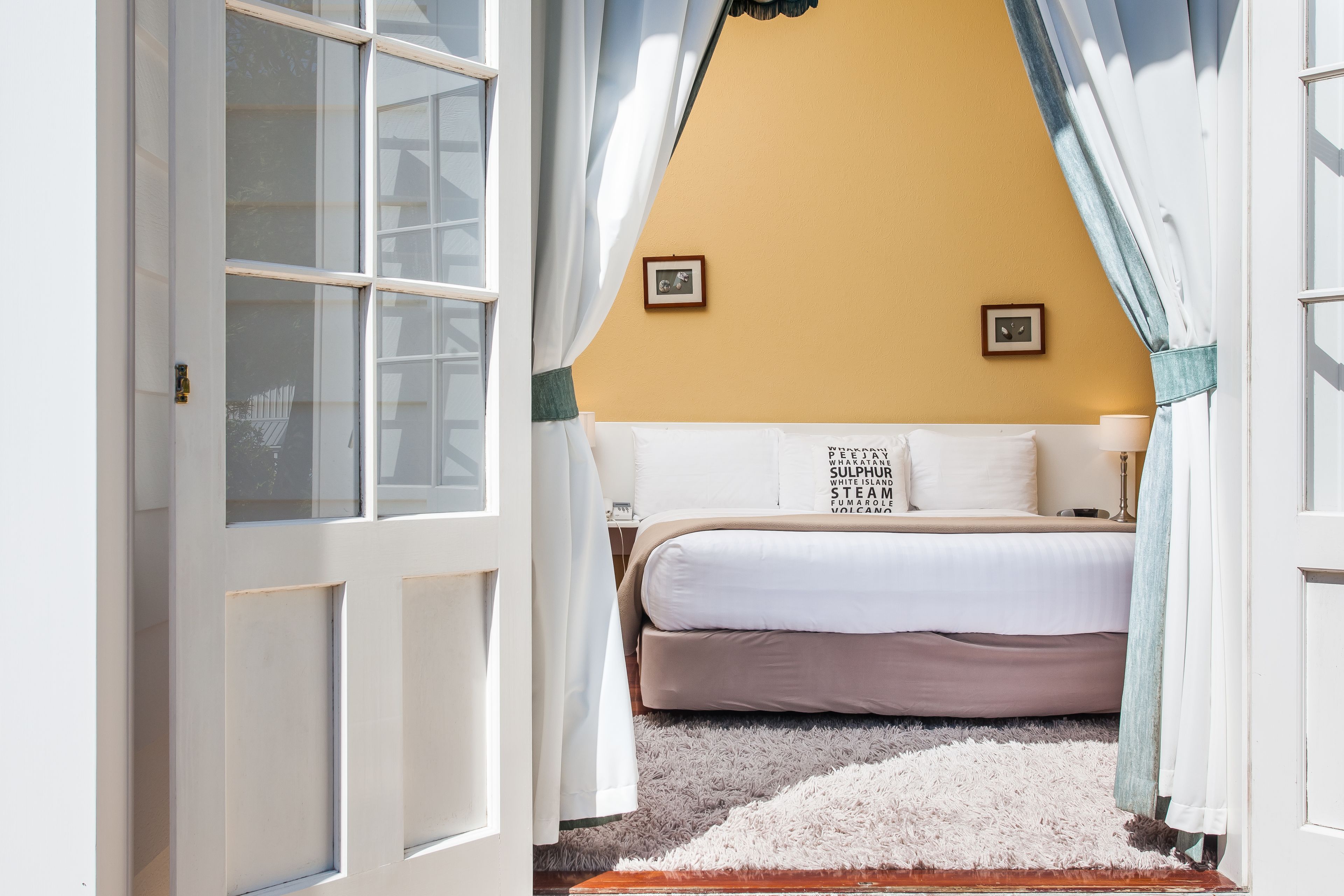 Un dormitorio con cama, una alfombra mullida y una ventana con cortinas.