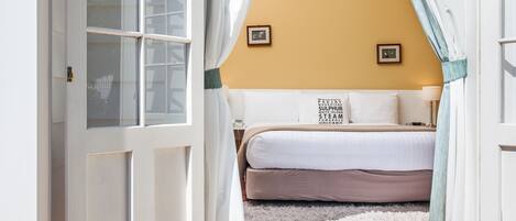 Un dormitorio con cama, una alfombra mullida y una ventana con cortinas.