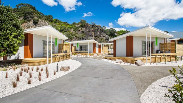 Un complexe hôtelier moderne doté de plusieurs chalets, chacun comprenant une terrasse en bois et une grande fenêtre.