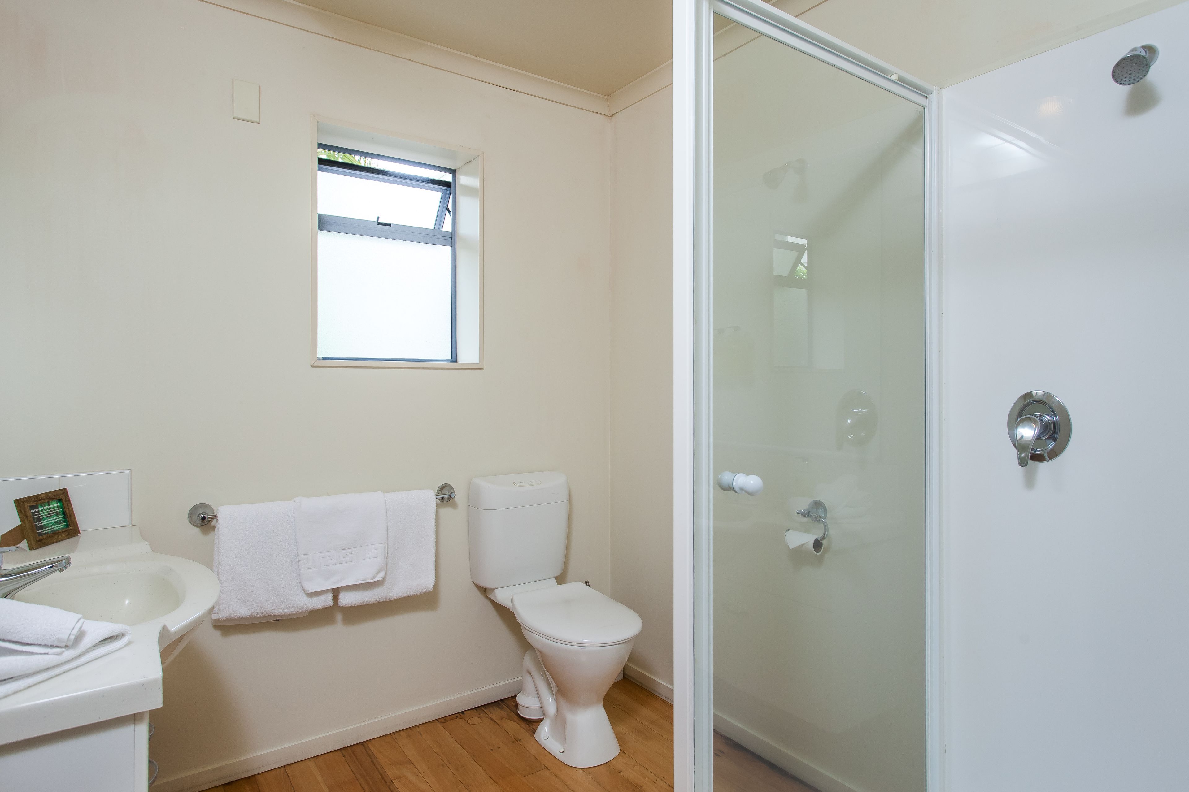 A bathroom with a toilet, sink, and glass shower enclosure.