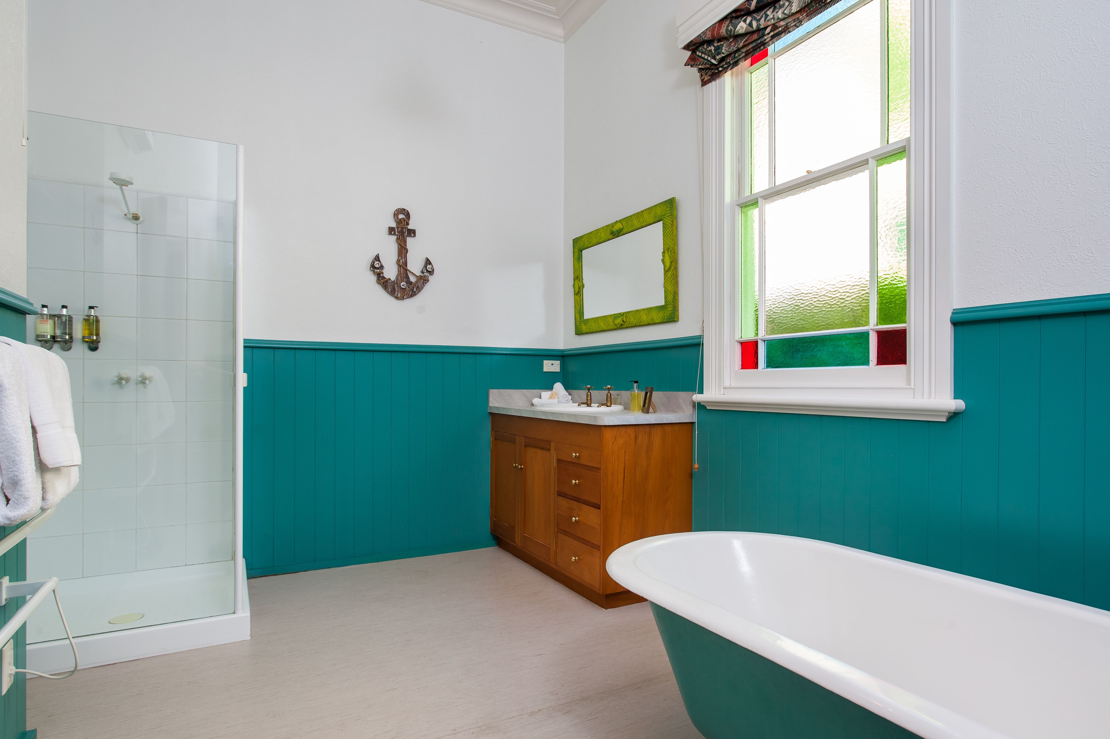A bathroom with a glass shower enclosure, a wooden vanity with a mirror, and a freestanding bathtub.