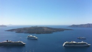 Escena costera con varios cruceros en el agua, cielo despejado e islas distantes.