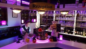A bar area with a 'Rezeption' sign, shelves with bottles, and a decorative centerpiece with pumpkins and a chef figure. - Hotel an der Hörn (Kiel)