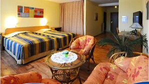A hotel room with a bed, a chair, a small table with a doily, and a potted plant. - Hotel an der Hörn (Kiel)
