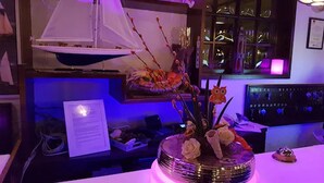 A bar area with a decorative centerpiece, a ship model, and a menu on the table. - Hotel an der Hörn (Kiel)