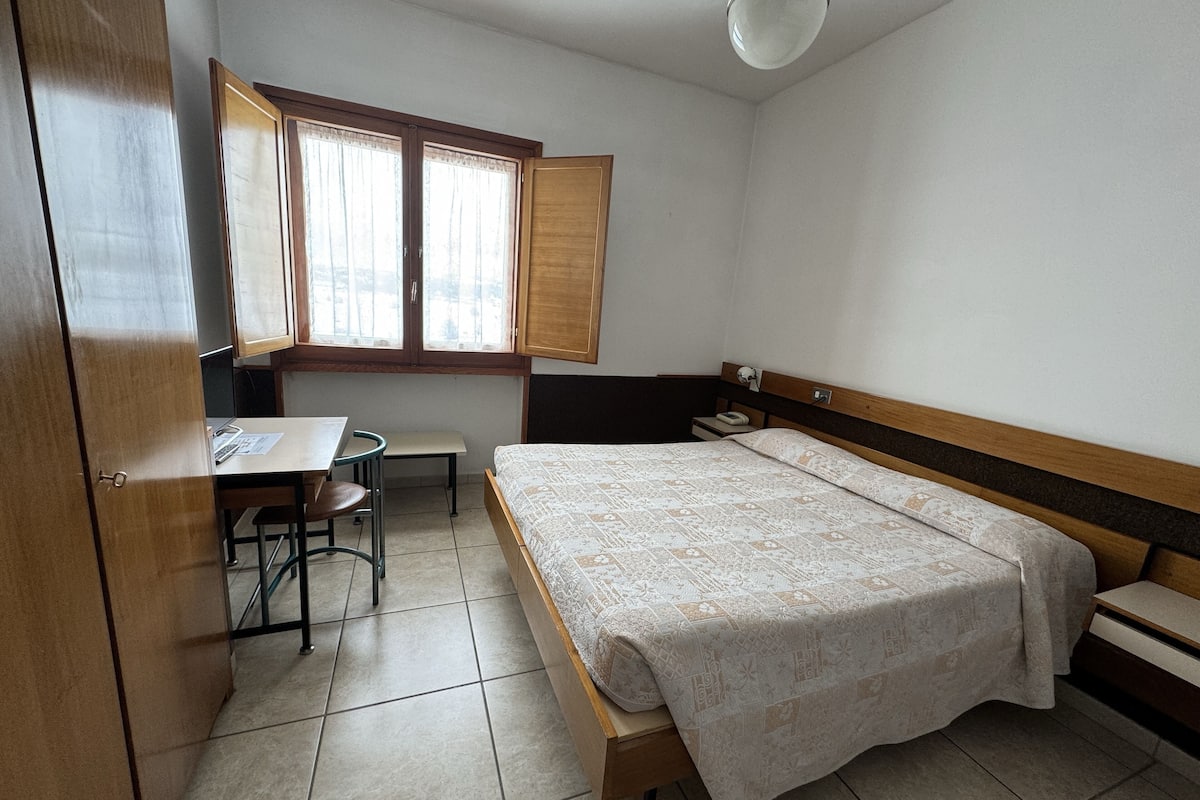 A small, tidy room with a bed, a desk, and a chair.