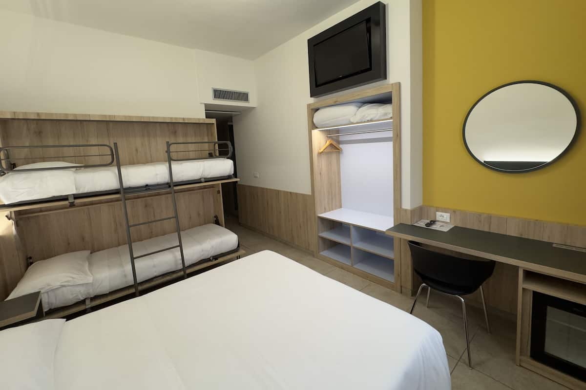 A bunk bed room with a desk, a mirror, and a TV.