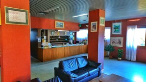Uma área de recepção com balcão de madeira, sofá de couro azul e quadros nas paredes.