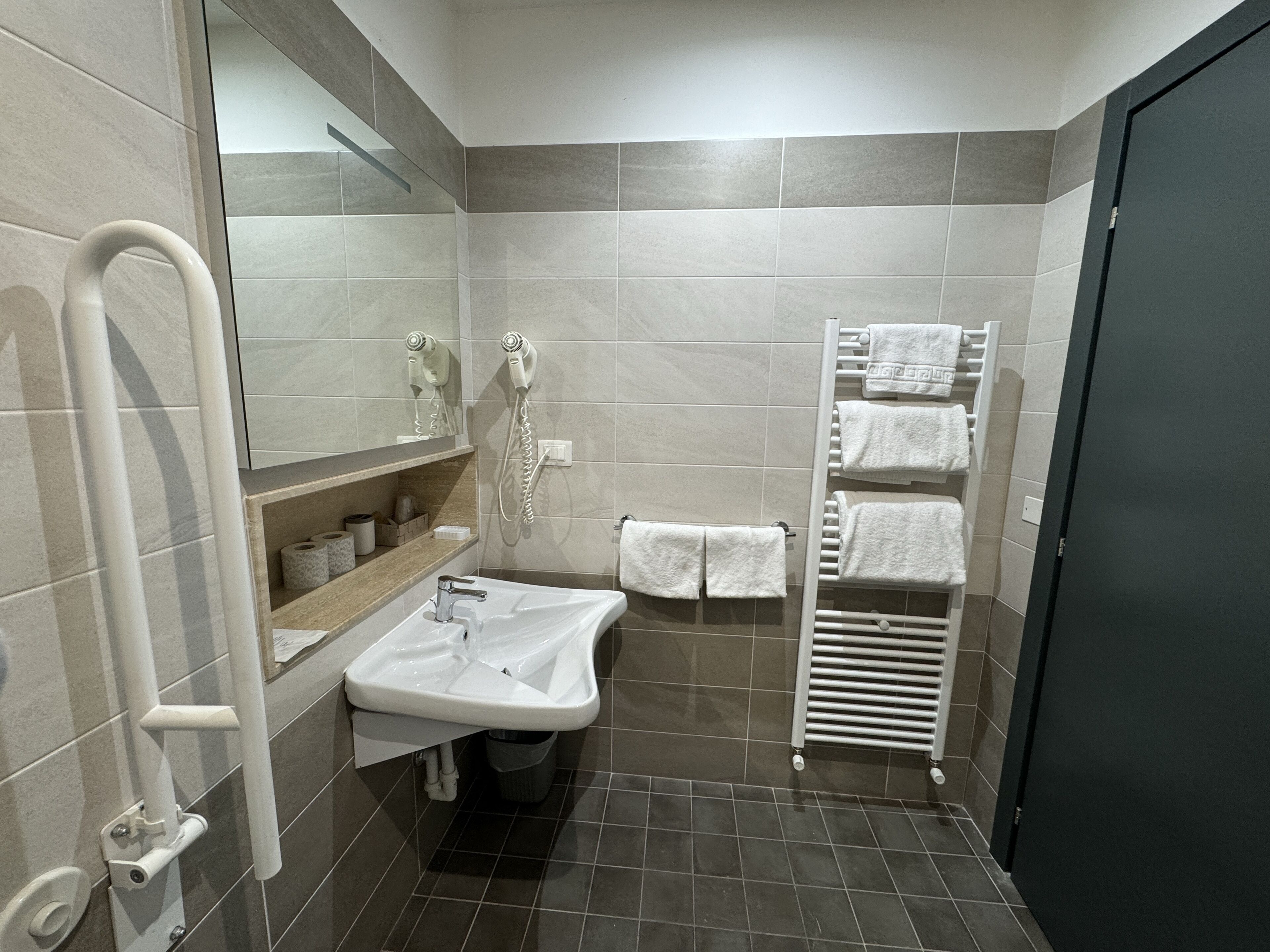 Un bagno moderno con lavandino, specchio, porta asciugamani e zona doccia.