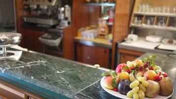 A marble countertop with a plate of assorted fruits and a wine glass.