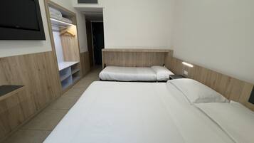 Habitación de hotel con dos camas, un televisor montado en la pared, un armario y una puerta que da a otra habitación.