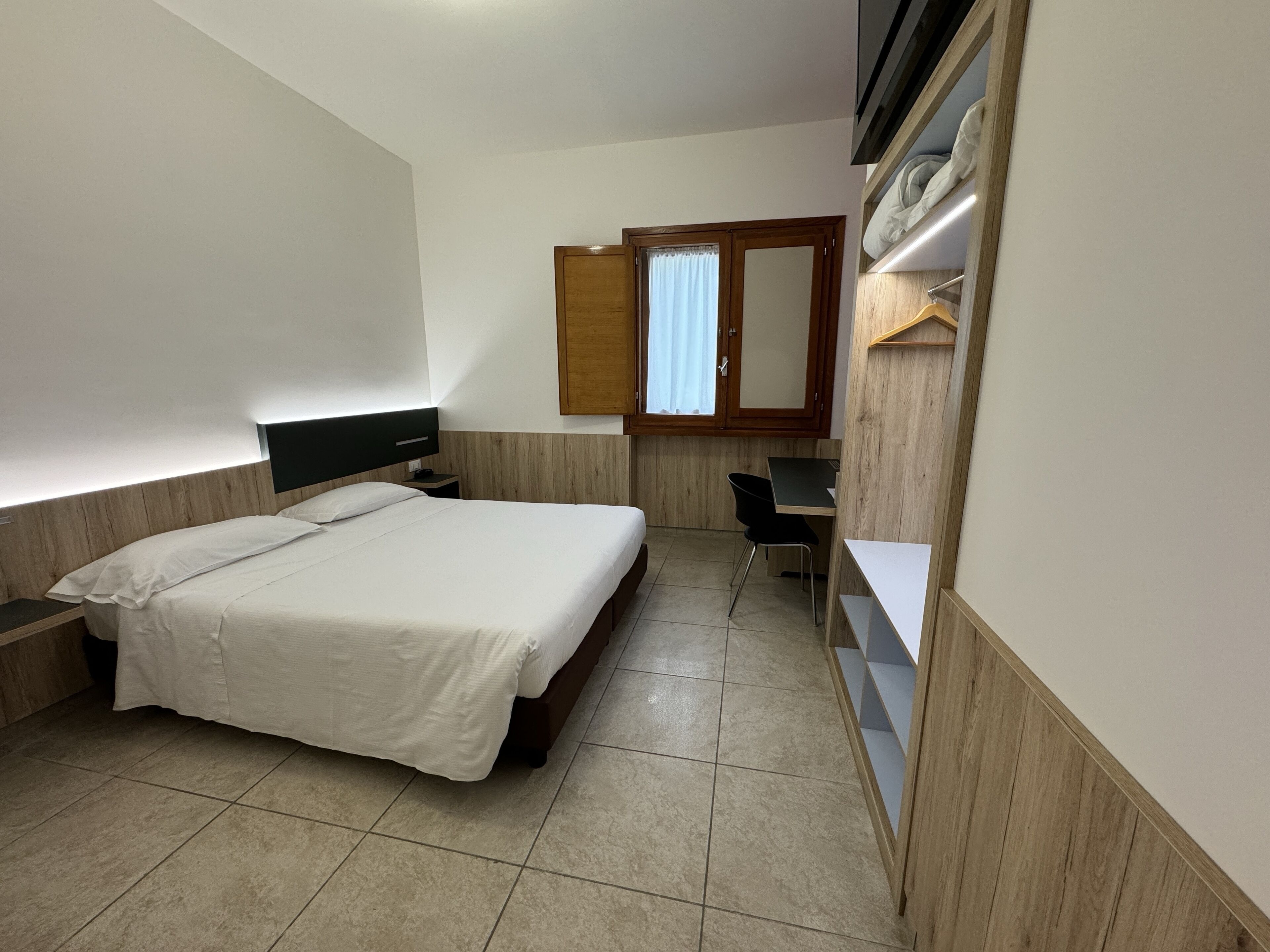 A bedroom with a bed, a desk, and a wardrobe.