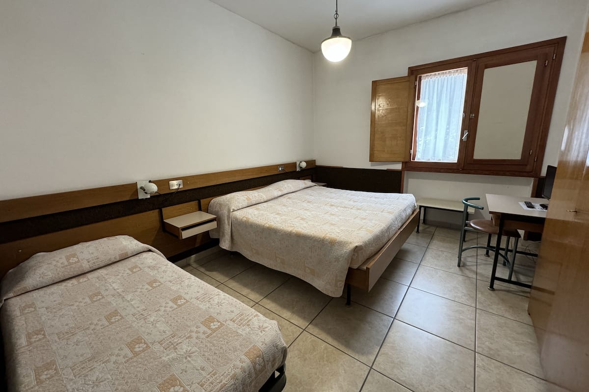 A simple, clean room with two beds, a desk, and a chair.