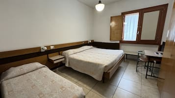 Quarto simples e limpo com duas camas, uma escrivaninha e uma cadeira.