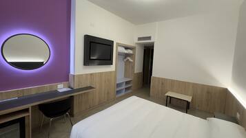 Una moderna camera d'albergo con un letto, una scrivania, una sedia, una televisione e un armadio.