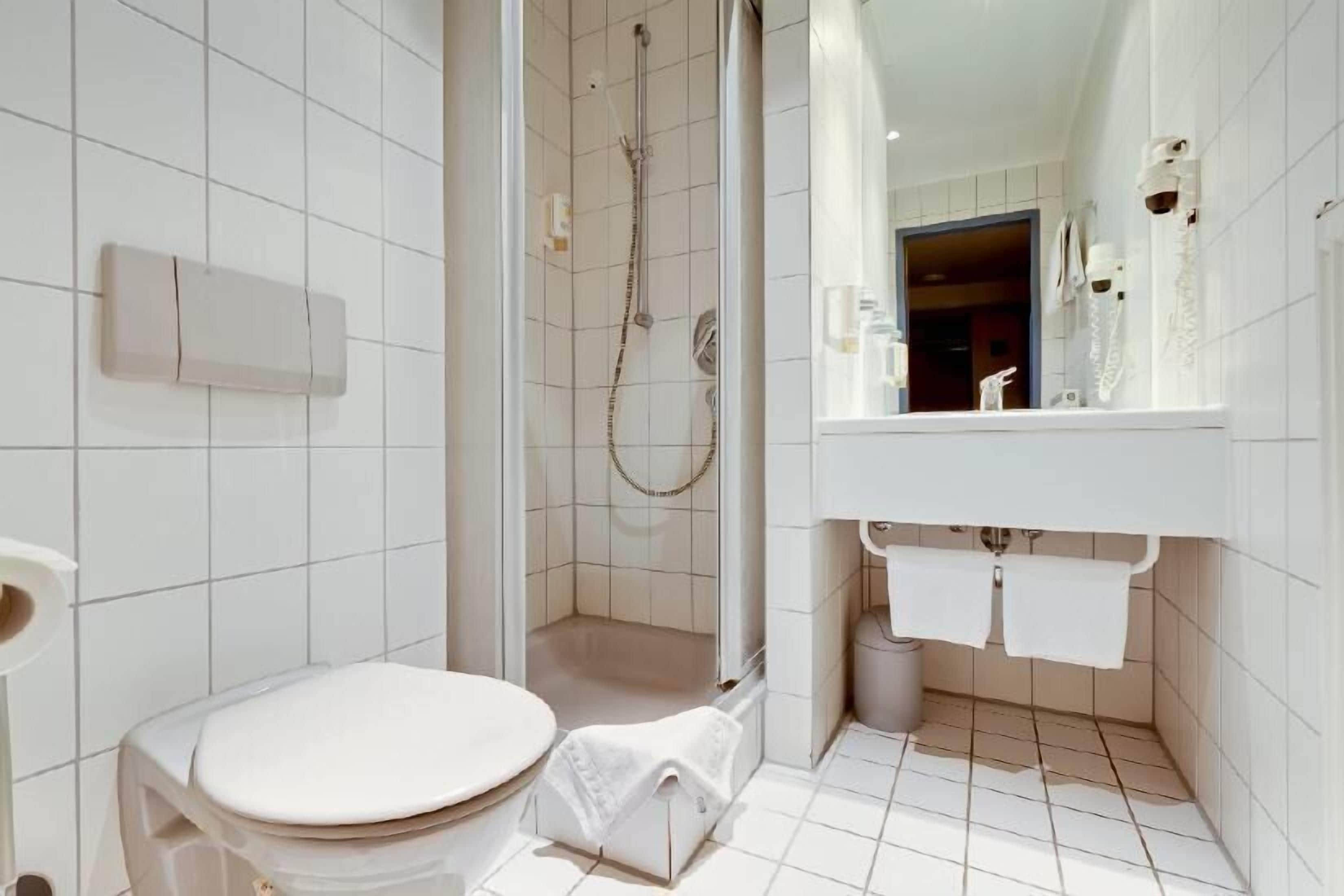 A modern bathroom with a toilet, shower, and sink.