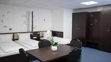 Habitación de hotel con dos camas, una mesa de comedor, sillas, un armario y una decoración de temática natural en la pared.