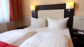 Une chambre d’hôtel avec un grand lit, deux tables de chevet et deux lampes fixées au mur.