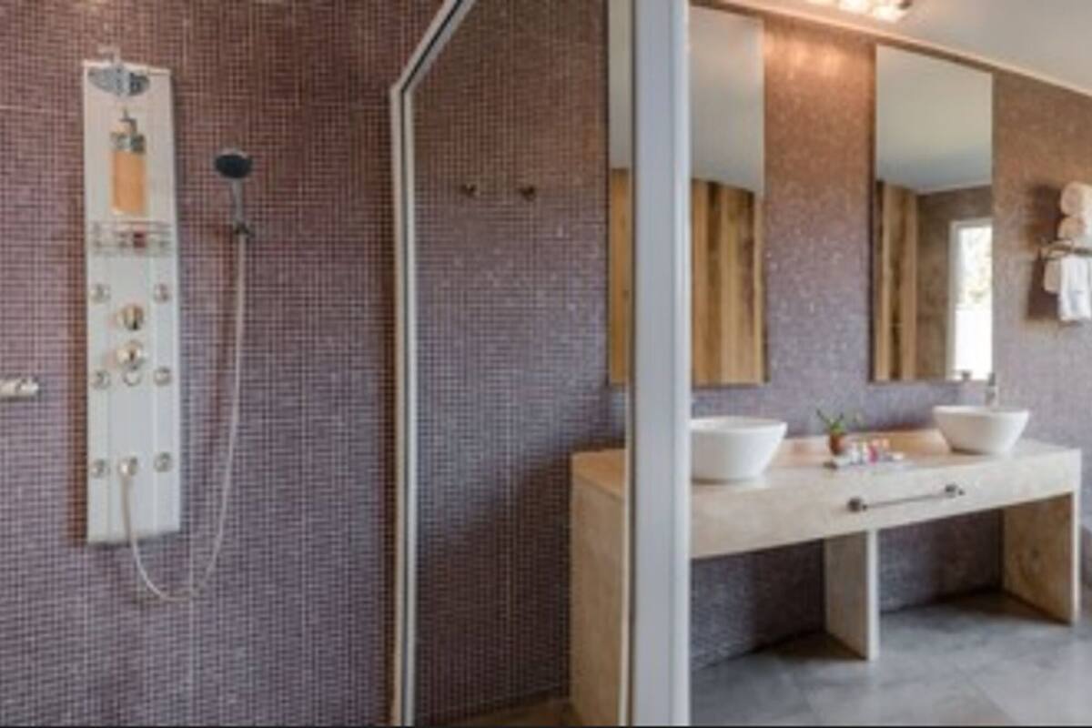A modern bathroom with a shower, two sinks, a large mirror, and a bathtub.