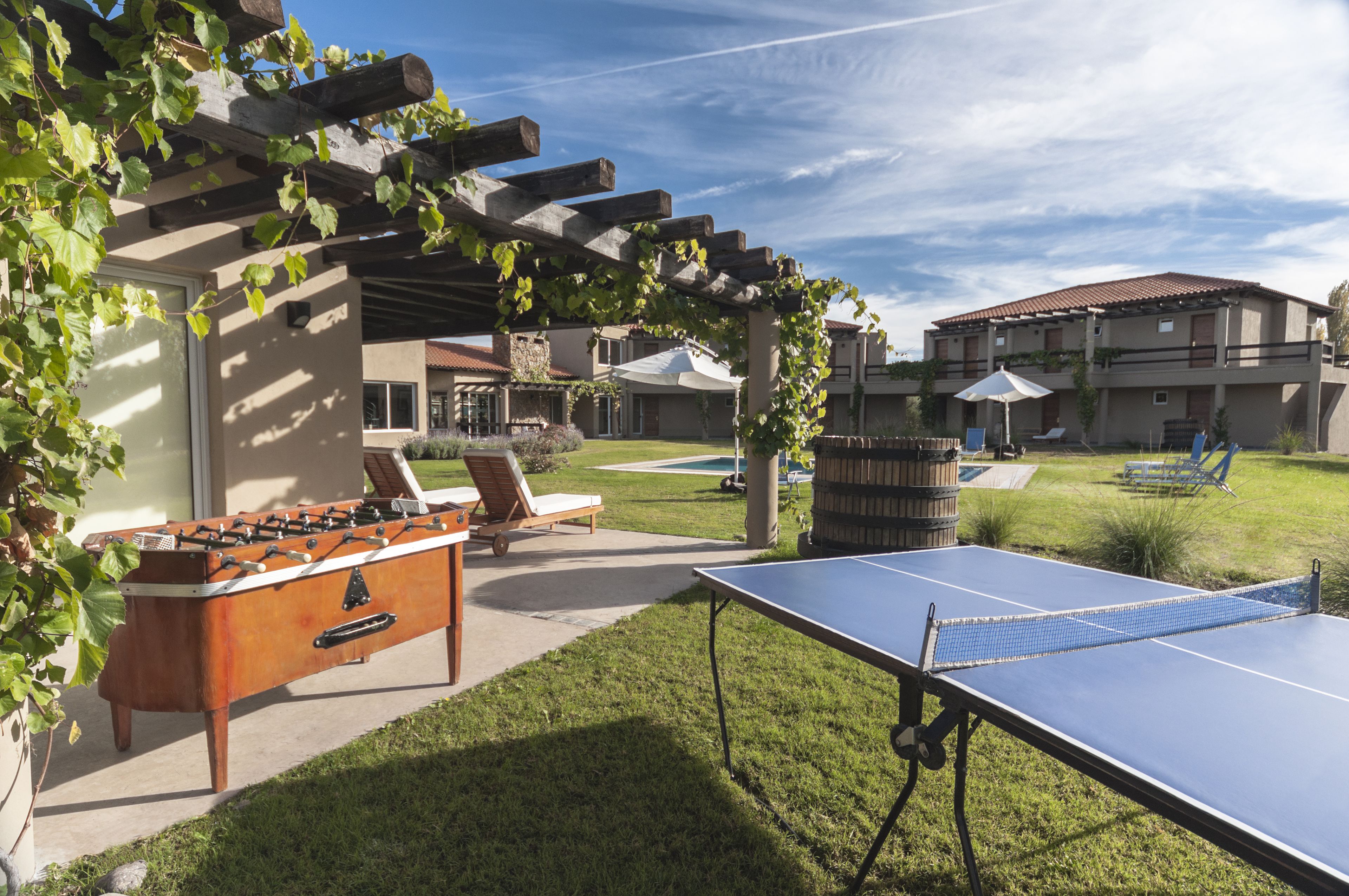 Un área recreativa al aire libre con mesa de futbolín, mesa de ping pong y sillones.