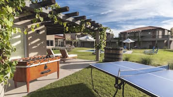 Un área recreativa al aire libre con mesa de futbolín, mesa de ping pong y sillones.