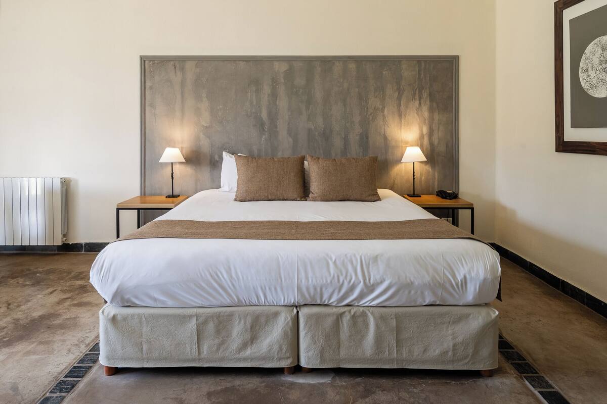 A large bed with two nightstands, each with a lamp, in a hotel room.
