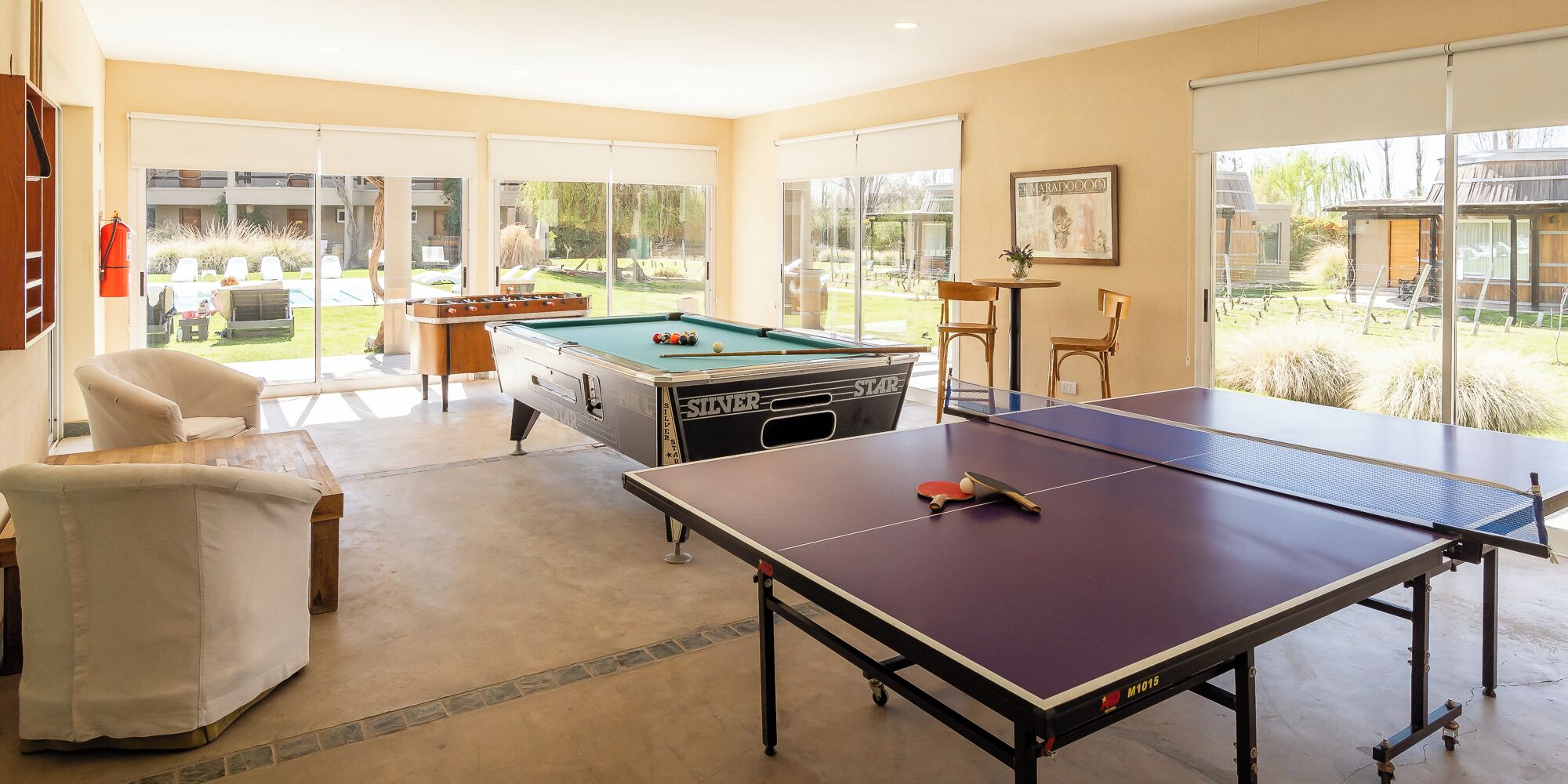A spacious indoor area with a pool table, a foosball table, and a ping pong table.