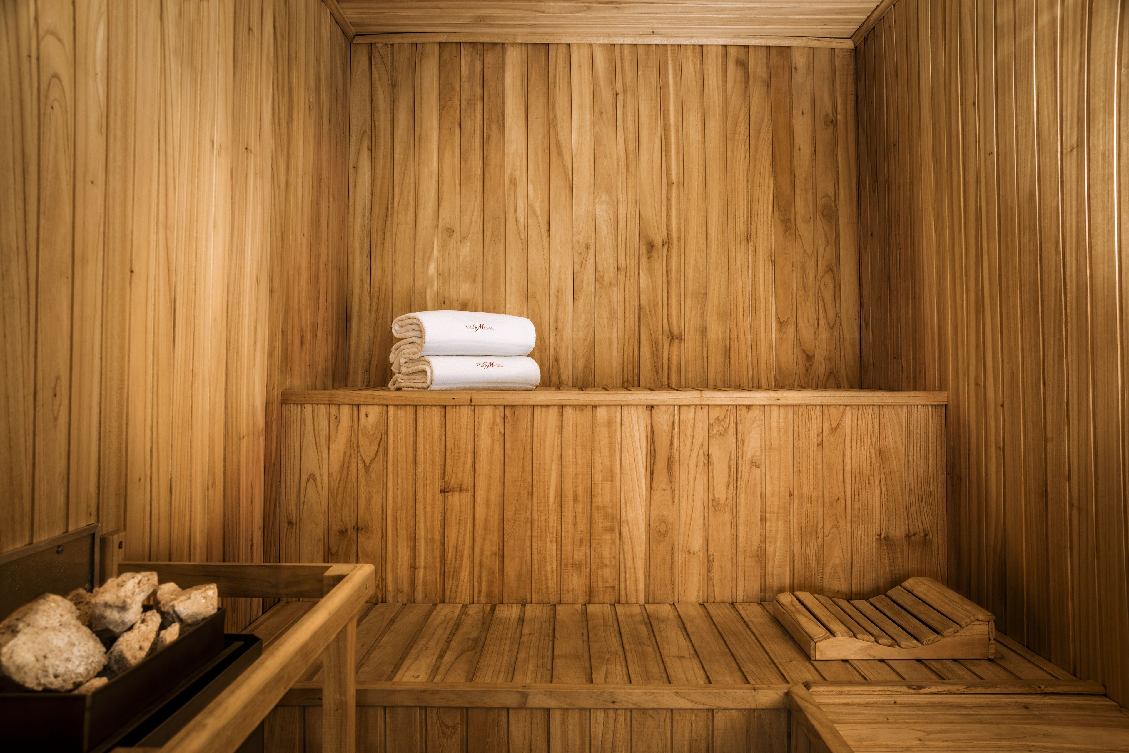 A wooden sauna with benches and a shelf holding towels.