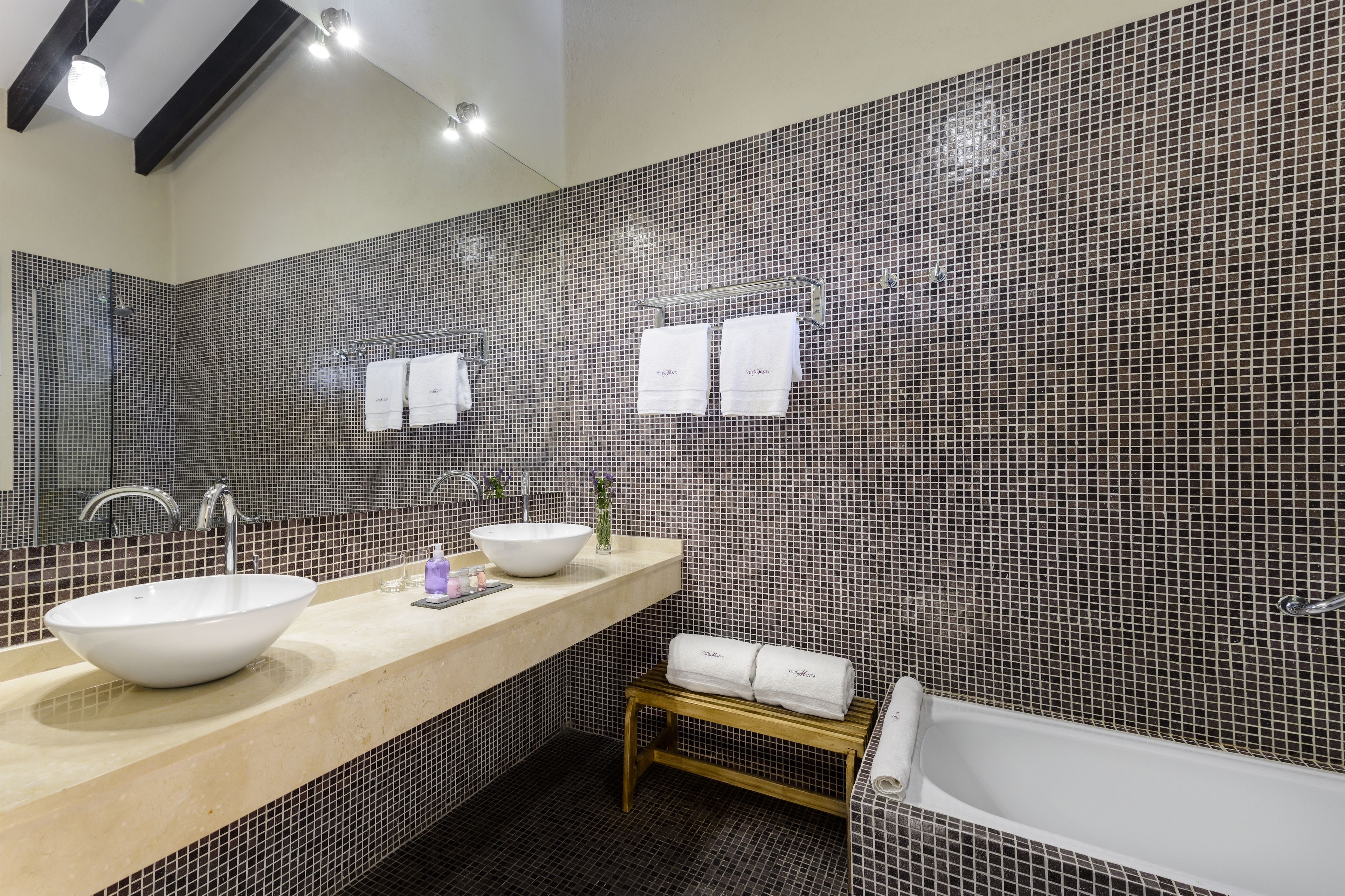 Une salle de bain moderne avec deux lavabos, un grand miroir et une baignoire.