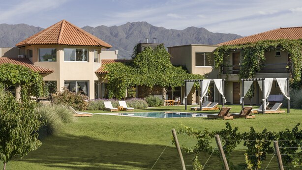 A resort with multiple buildings, a swimming pool, and a mountainous backdrop. - Villa Mansa Wine Hotel (Luján de Cuyo)