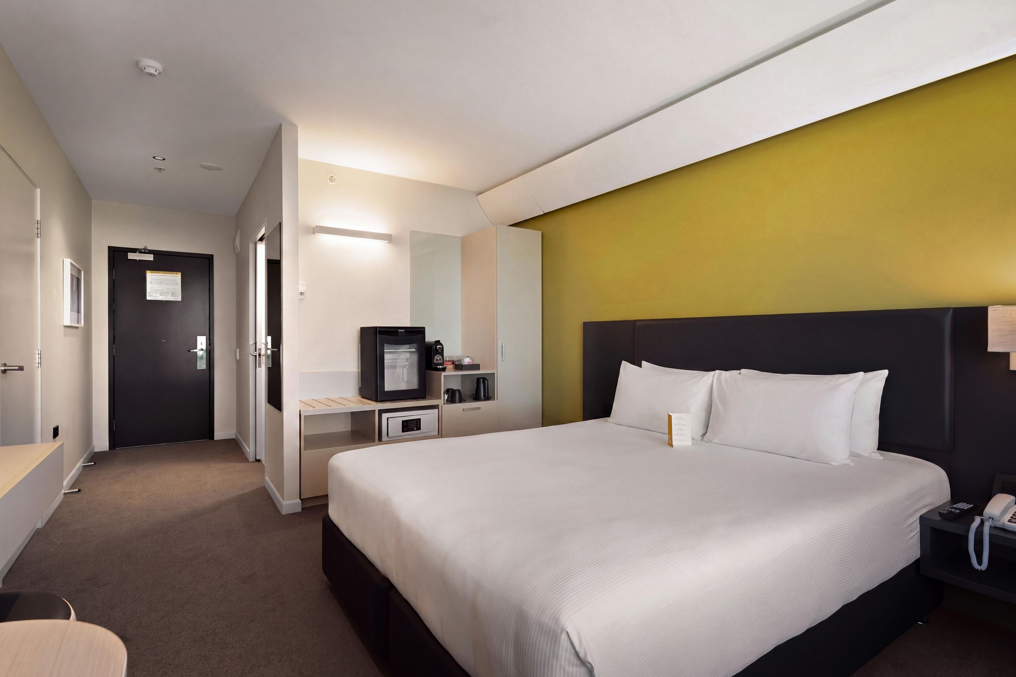 Ein Hotelzimmer mit Bett, Schreibtisch, Fernseher und Telefon.