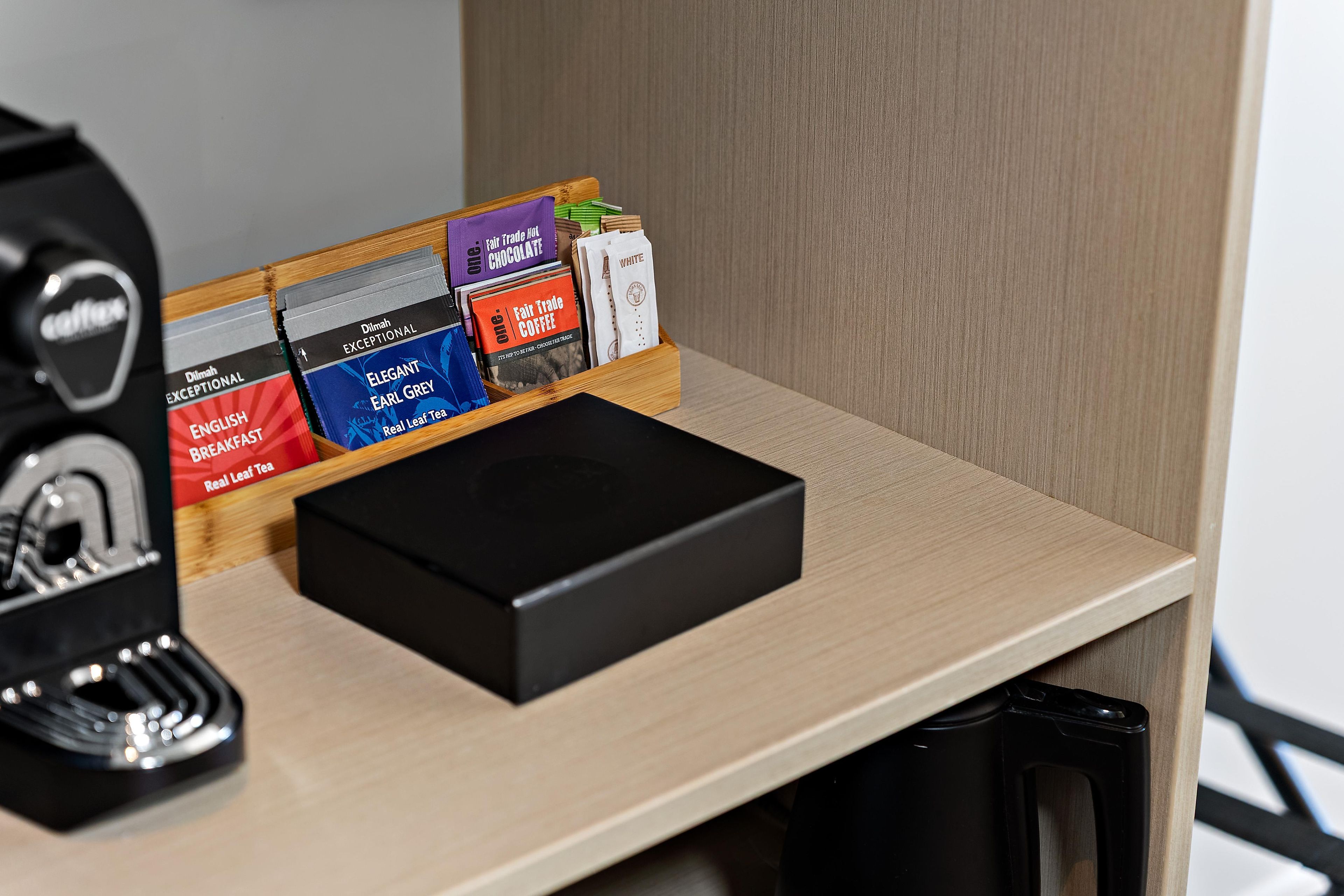 A coffee machine and a tray with various coffee and tea products.