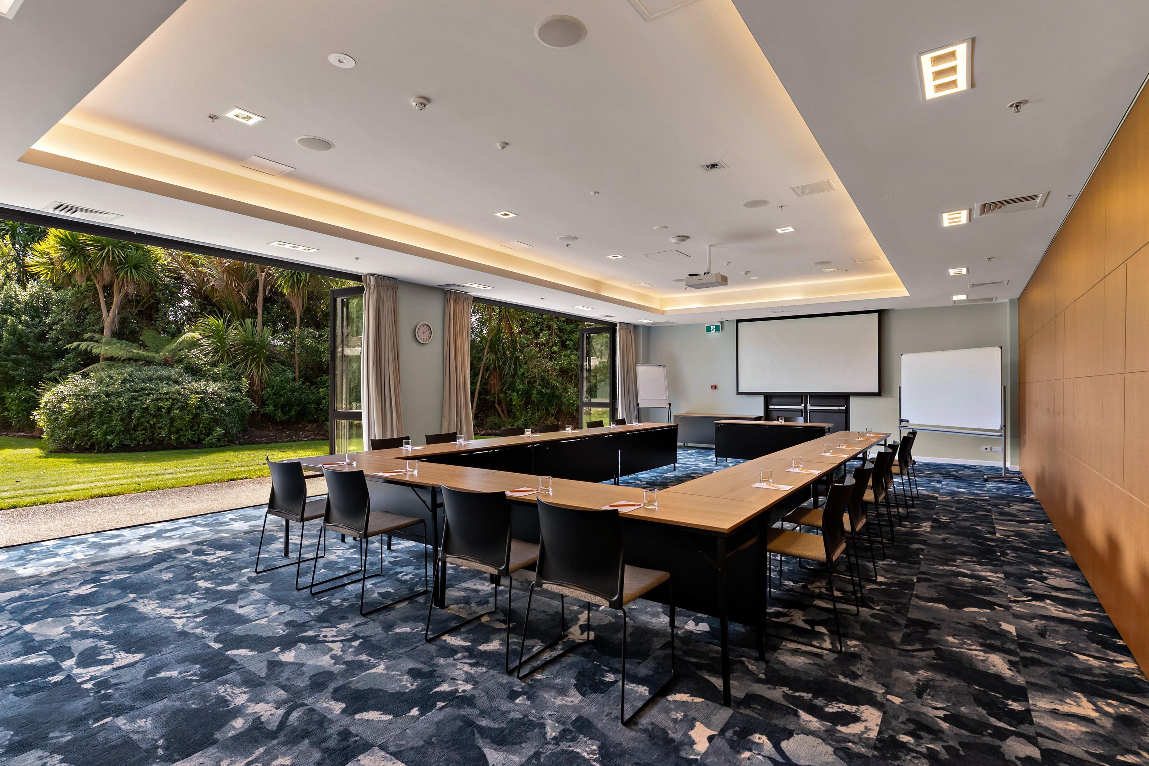 A conference room with a long table, chairs, a projector screen, and a whiteboard.