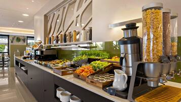 A buffet area with various food items, a coffee machine, and a juice dispenser.