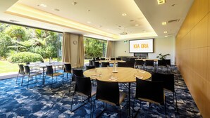 A conference room with round tables, black chairs, and a projector screen displaying "KIA ORA". - Sudima Auckland Airport (Auckland)