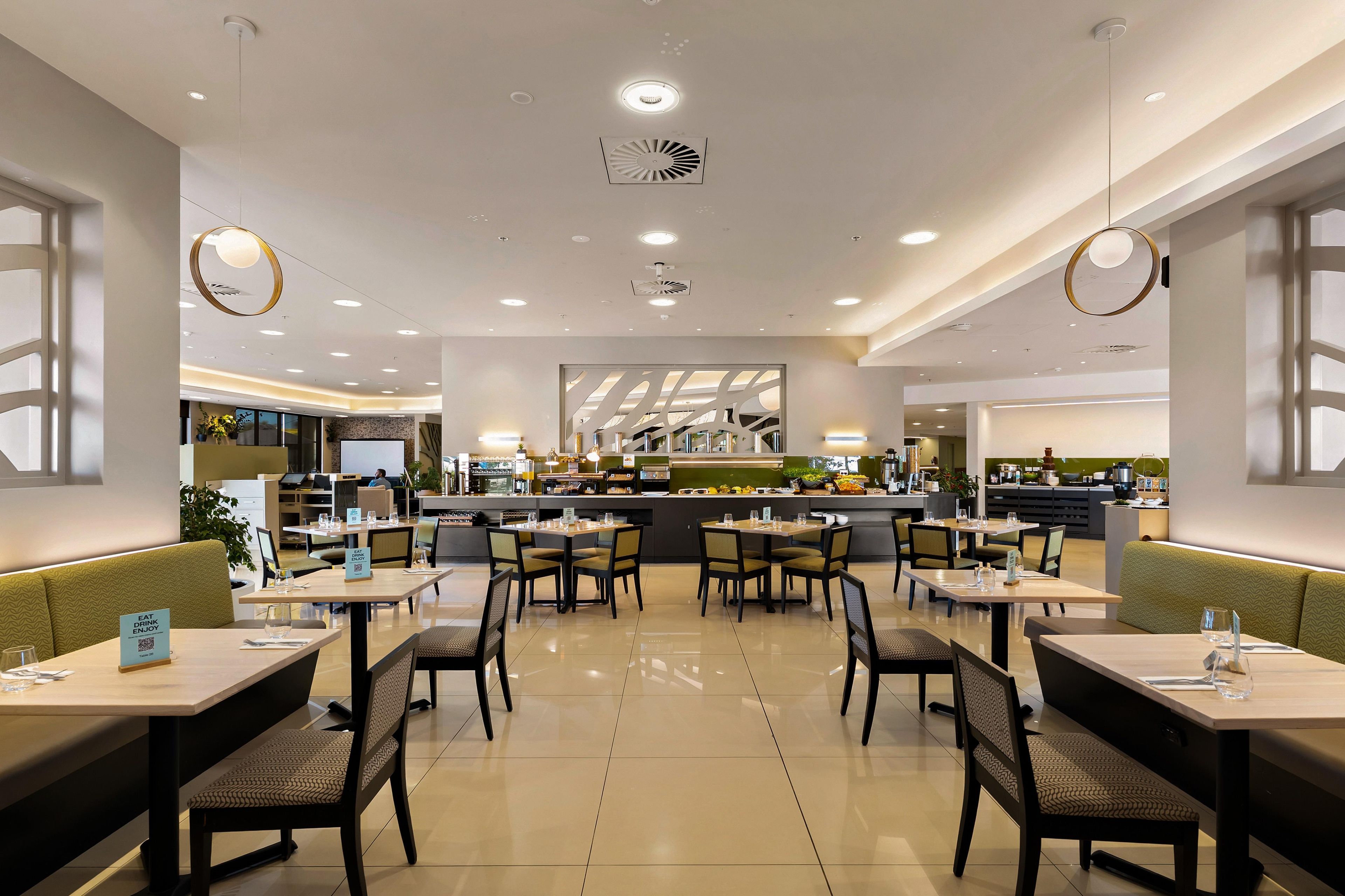 Un interior de restaurante moderno con varias mesas y cabinas, una zona de bar central y un ambiente limpio y bien iluminado.