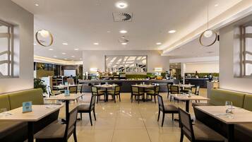 Un interior de restaurante moderno con varias mesas y cabinas, una zona de bar central y un ambiente limpio y bien iluminado.