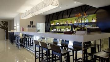 Eine moderne Bar mit einer langen Theke, mehreren Barhocker und einer Auswahl an Spirituosenflaschen.