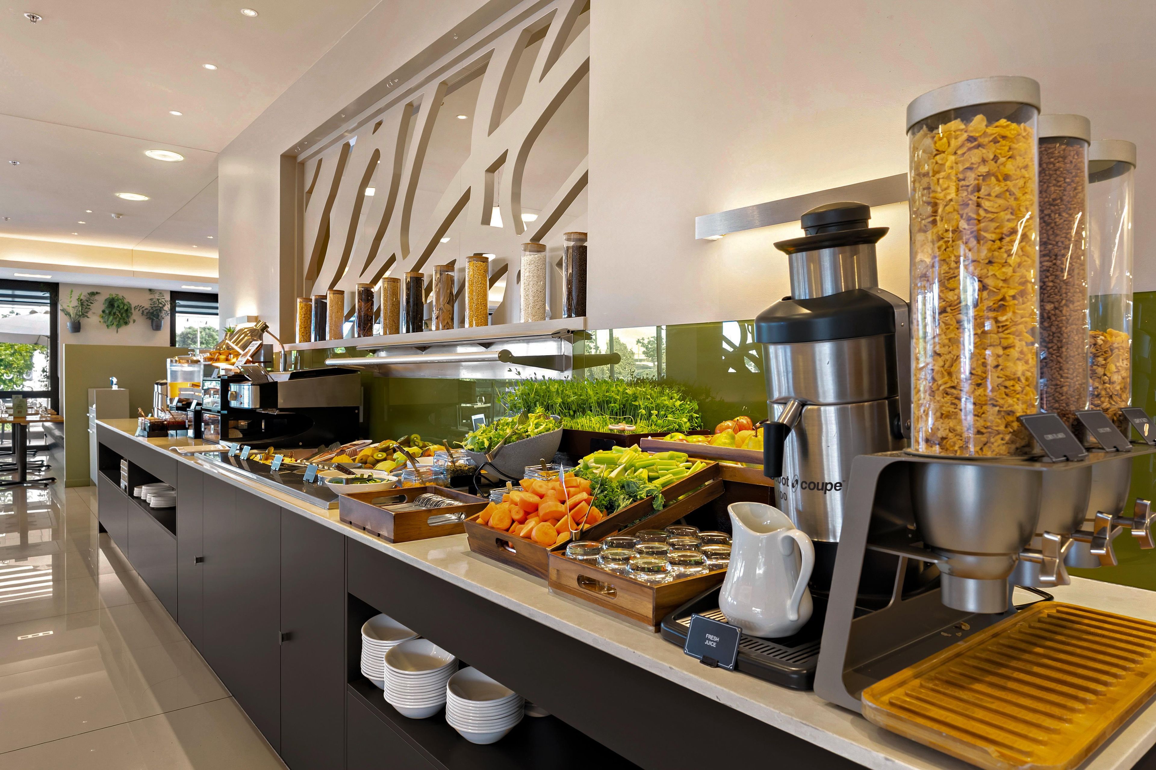 A buffet area with various food items, a coffee machine, and a juice dispenser.