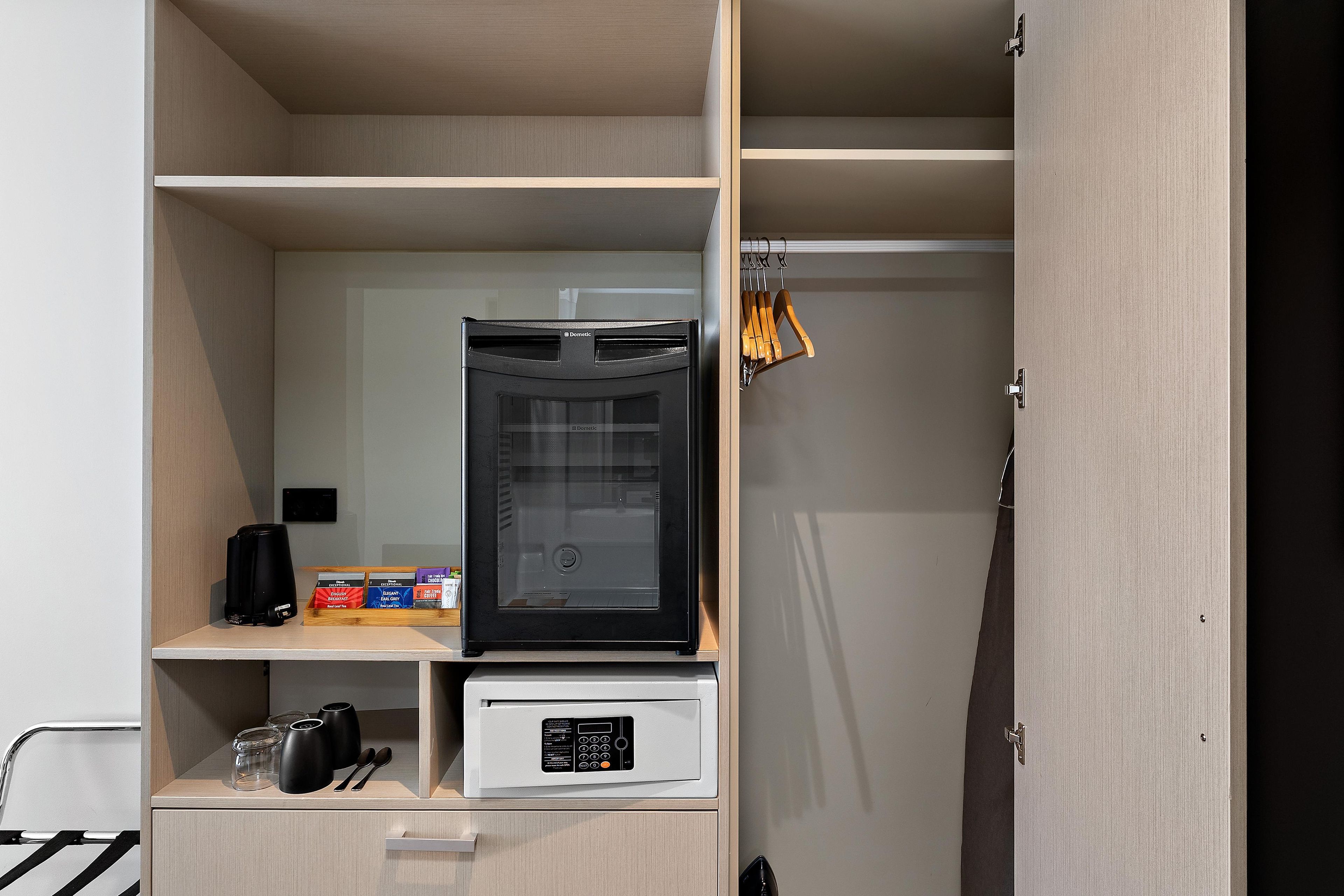 Una kitchenette compacta con cafetera, cápsulas de té y café, y microondas.