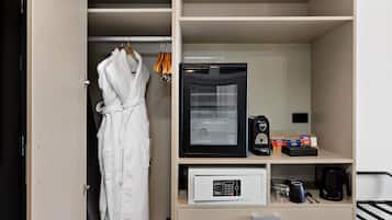 Habitación de hotel con una bata colgada, una cafetera y un microondas sobre la encimera.