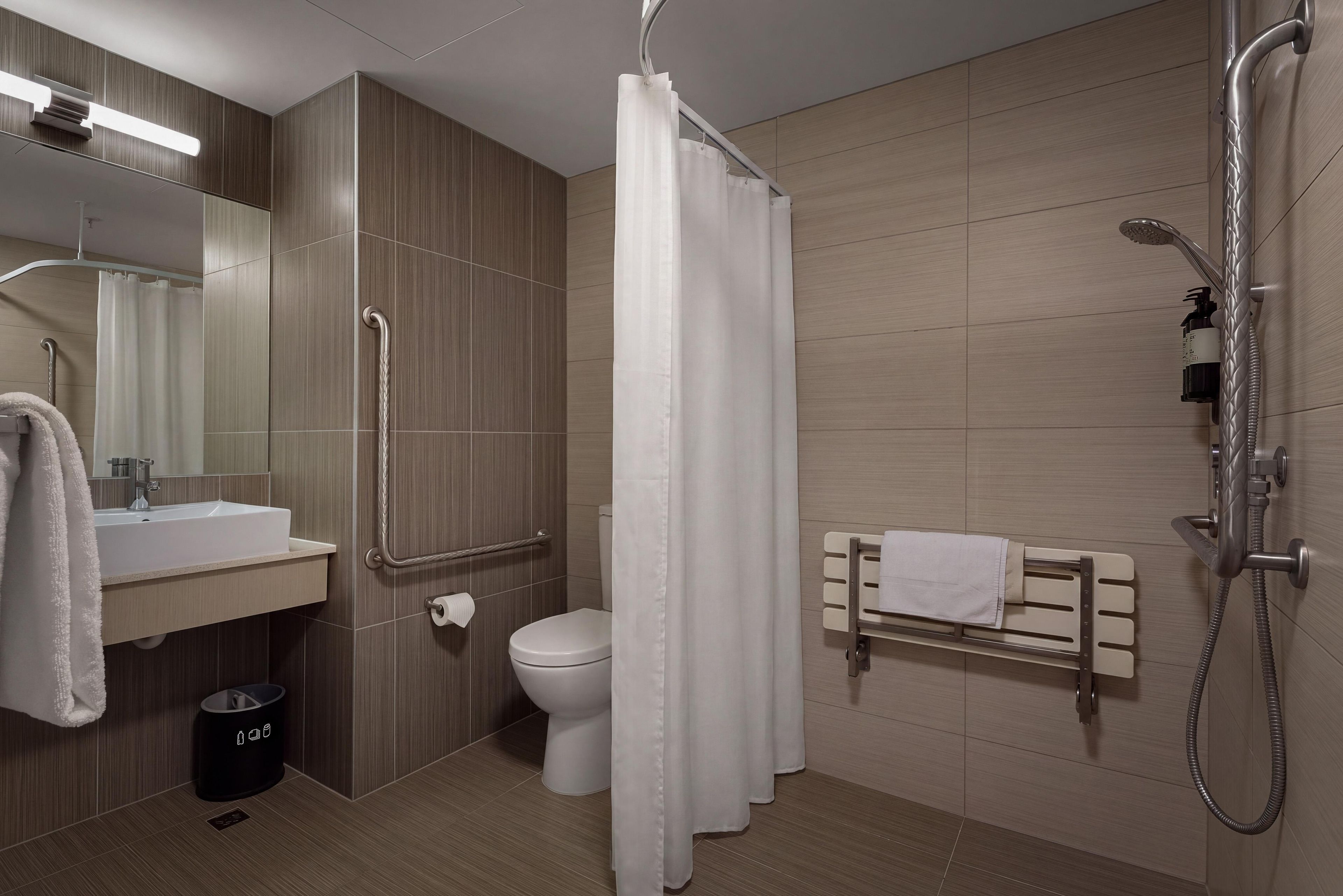 A modern bathroom with a shower, toilet, sink, and towel rack.
