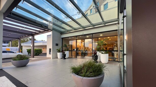 A hotel entrance with a covered outdoor area, large potted plants, and a glass facade. - Sudima Auckland Airport (Auckland)