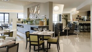 A modern restaurant with a central bar, dining tables with chairs, and a polished floor. - Sudima Auckland Airport (Auckland)
