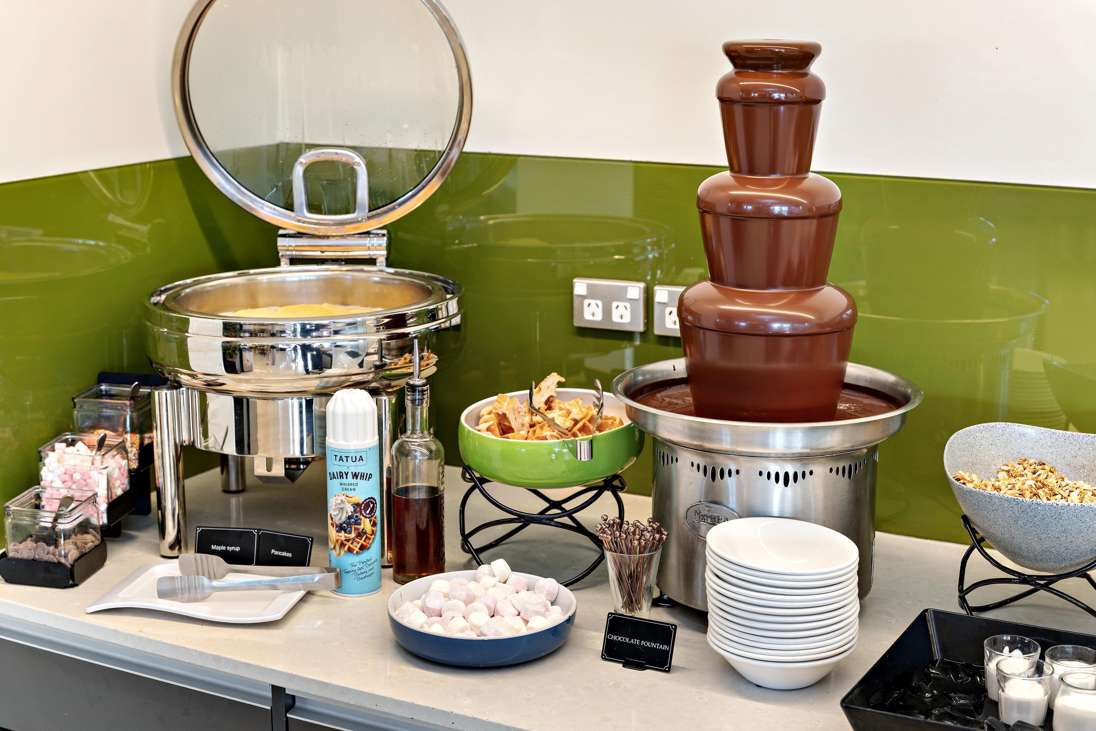 A buffet setup with various food items and a chocolate fountain.